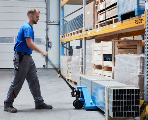 man moves blue pallet truck into storage
