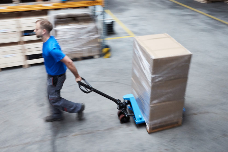 man pushes blue pallet truck into storage